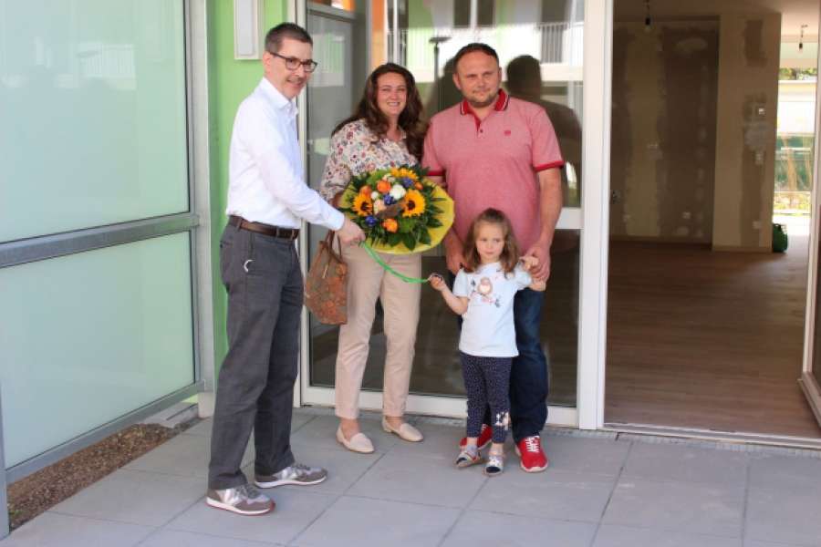 Der Vorstandsvorsitzende der Baugenossenschaft Langen eG, Wolf-Bodo Friers (links), übergibt den Schlüssel und einen Blumenstrauß an Familie Fleer (Svetlana Fleer, Ehemann Eugen Fleer und Tochter Arina). Foto: Baugenossenschaft Langen eG