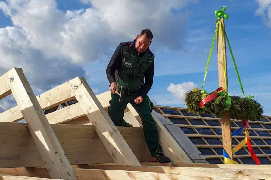 WIS-Hausmeister Mario Dietz schlägt den symbolisch letzten Nagel ein – neben dem Richtkranz. FOTO: WIS Wohnungsbaugesellschaft im Spreewald mbH